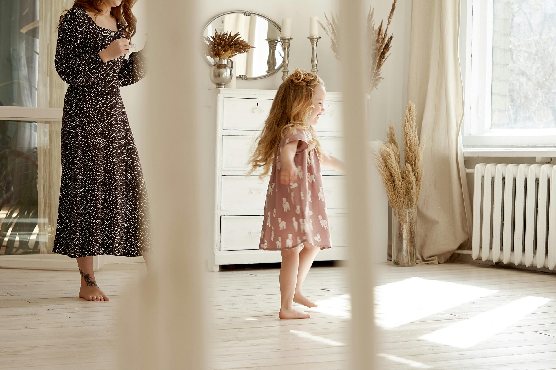 Charming indoor scene of a mother and daughter enjoying a sunny day in a stylish, airy room.